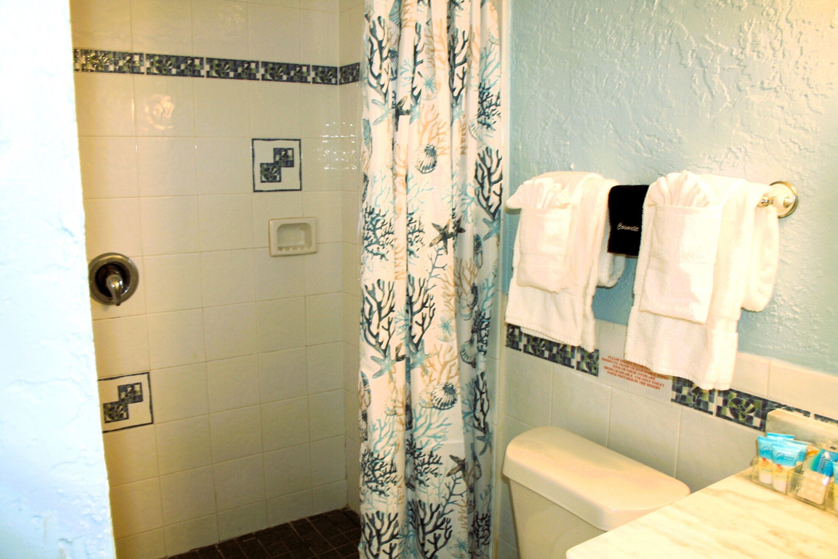 A bathroom with a shower, toilet, and sink.
