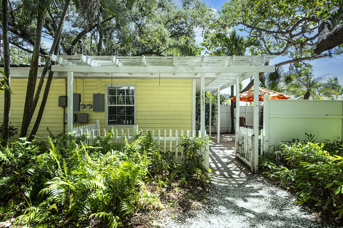 A yellow house with a white porch and a white picket fence.