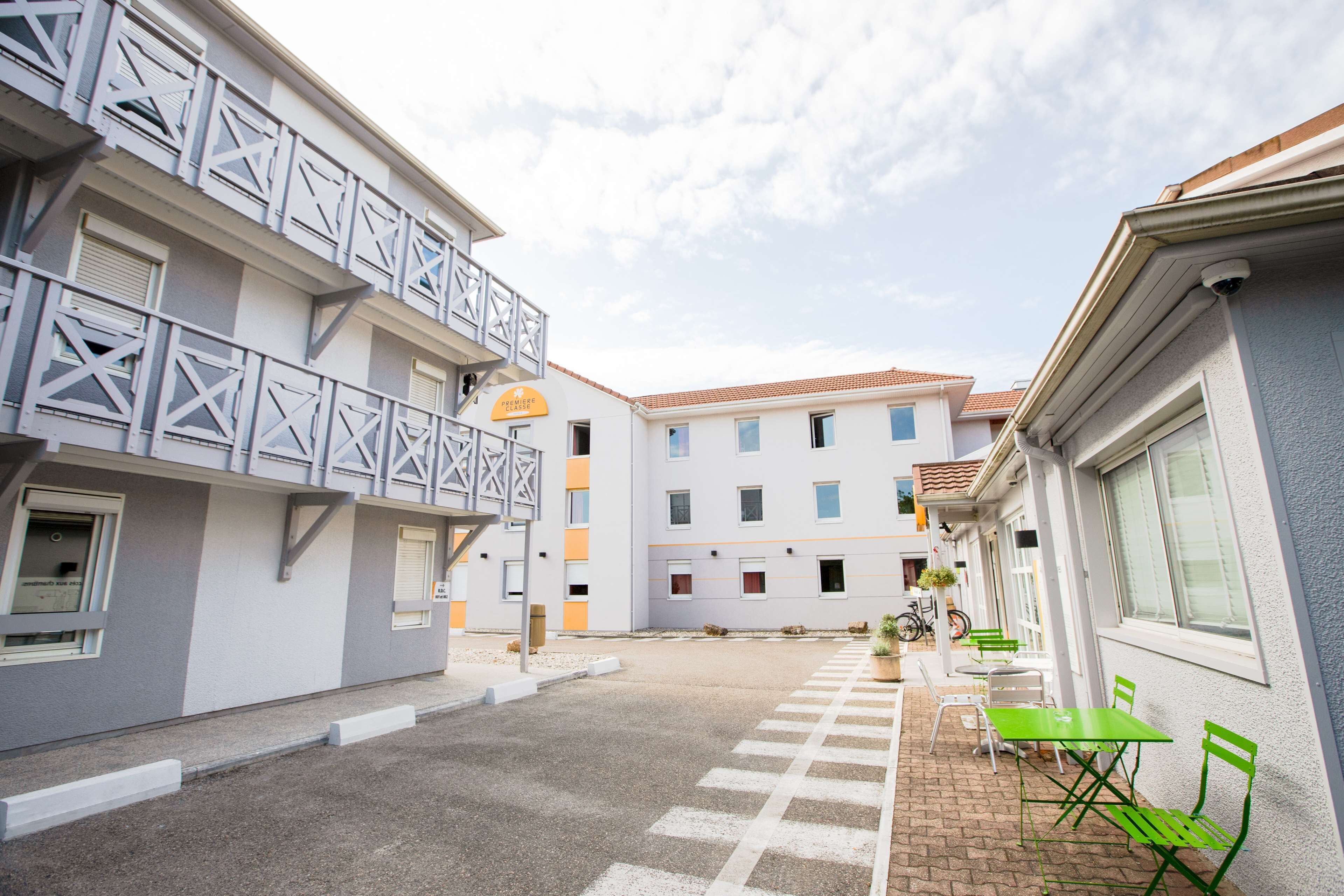 A courtyard with outdoor seating, a building with balconies, and a sign indicating a premium room.