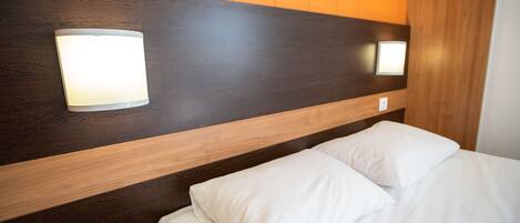 A hotel room with a wooden headboard, two wall-mounted lights, and a bed with white bedding.