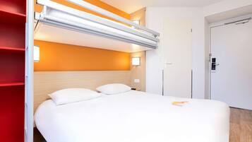 A hotel room with a bed, a red wardrobe, and a white door.