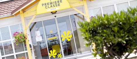 A hotel entrance with a yellow awning and a sign that reads "PREMIERE CLASSE HOTELS".