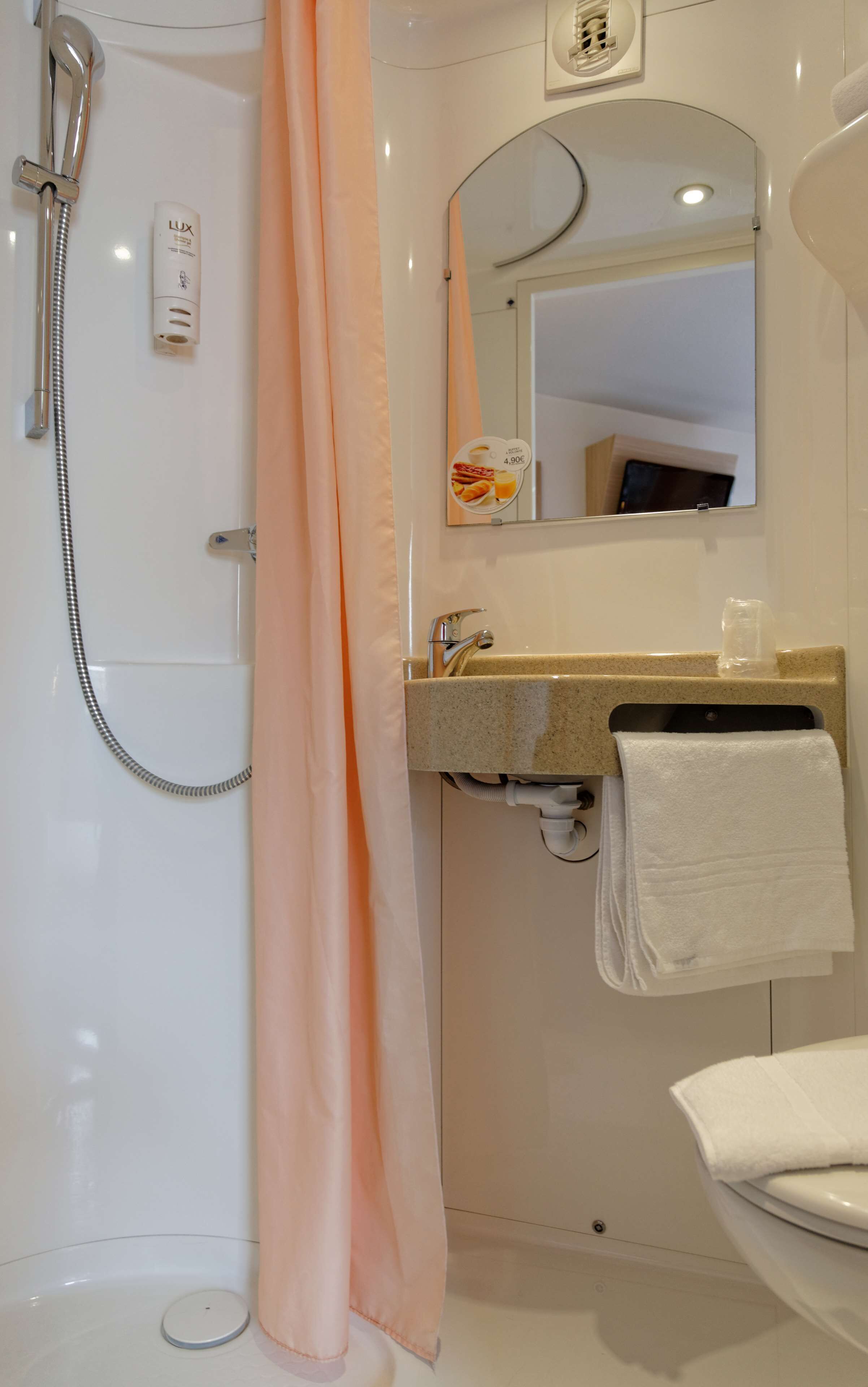 A bathroom with a shower, a sink with a towel, and a mirror.