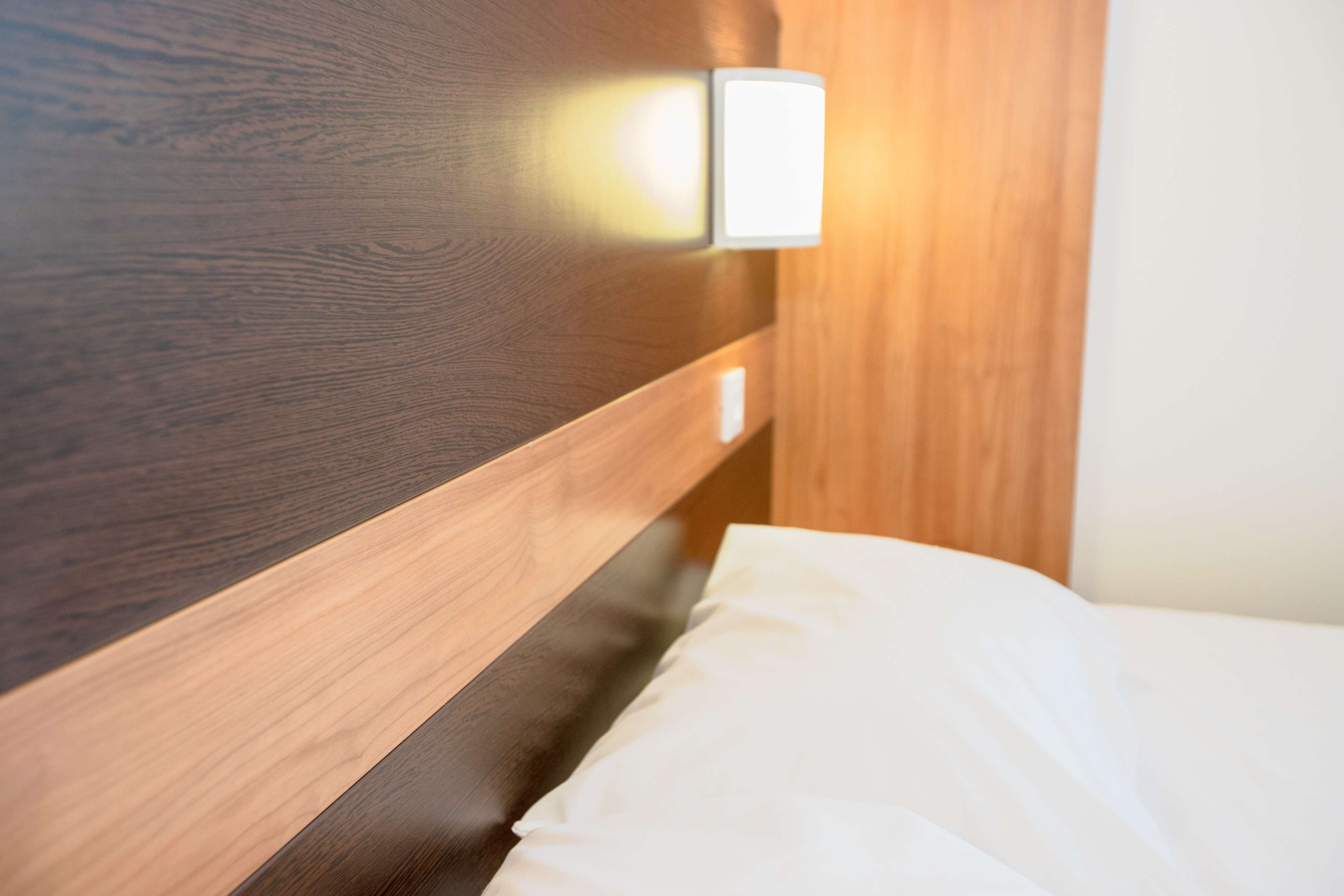 A wooden headboard with a light fixture and a white pillow.
