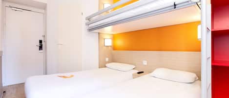 A hotel room with a bunk bed, a bedside table, and a wall-mounted light fixture.