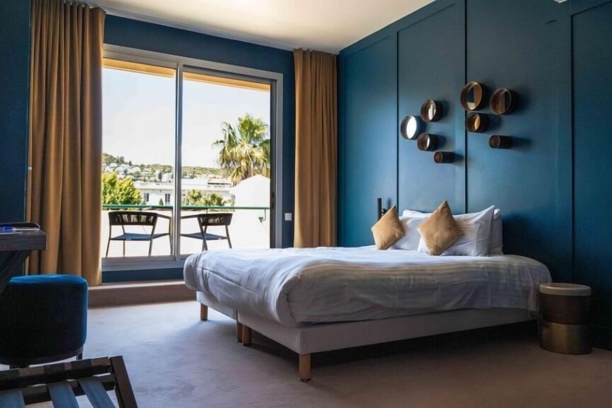 Un dormitorio con cama, escritorio y vistas al exterior.