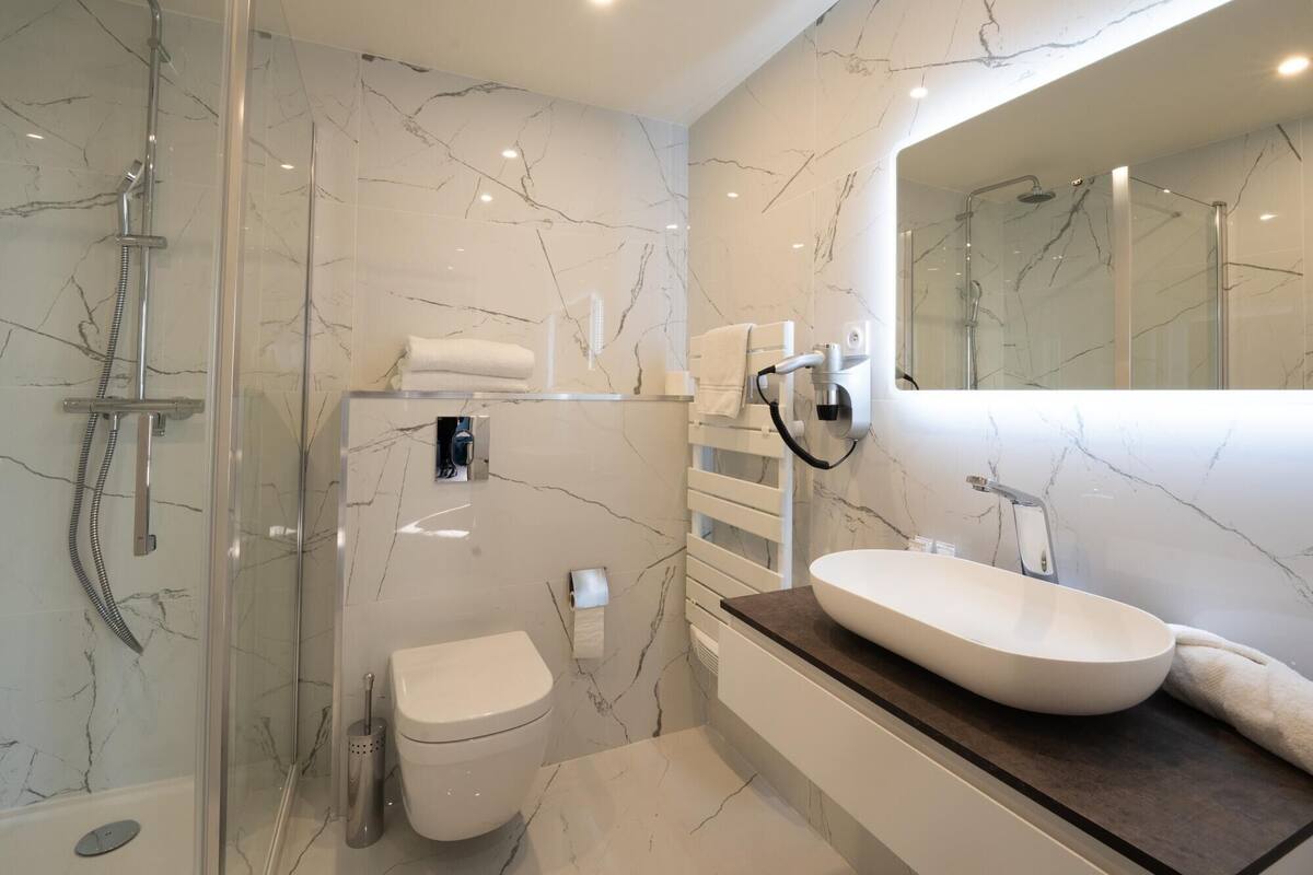 A modern bathroom with a glass-enclosed shower, a toilet, and a vanity with a sink.