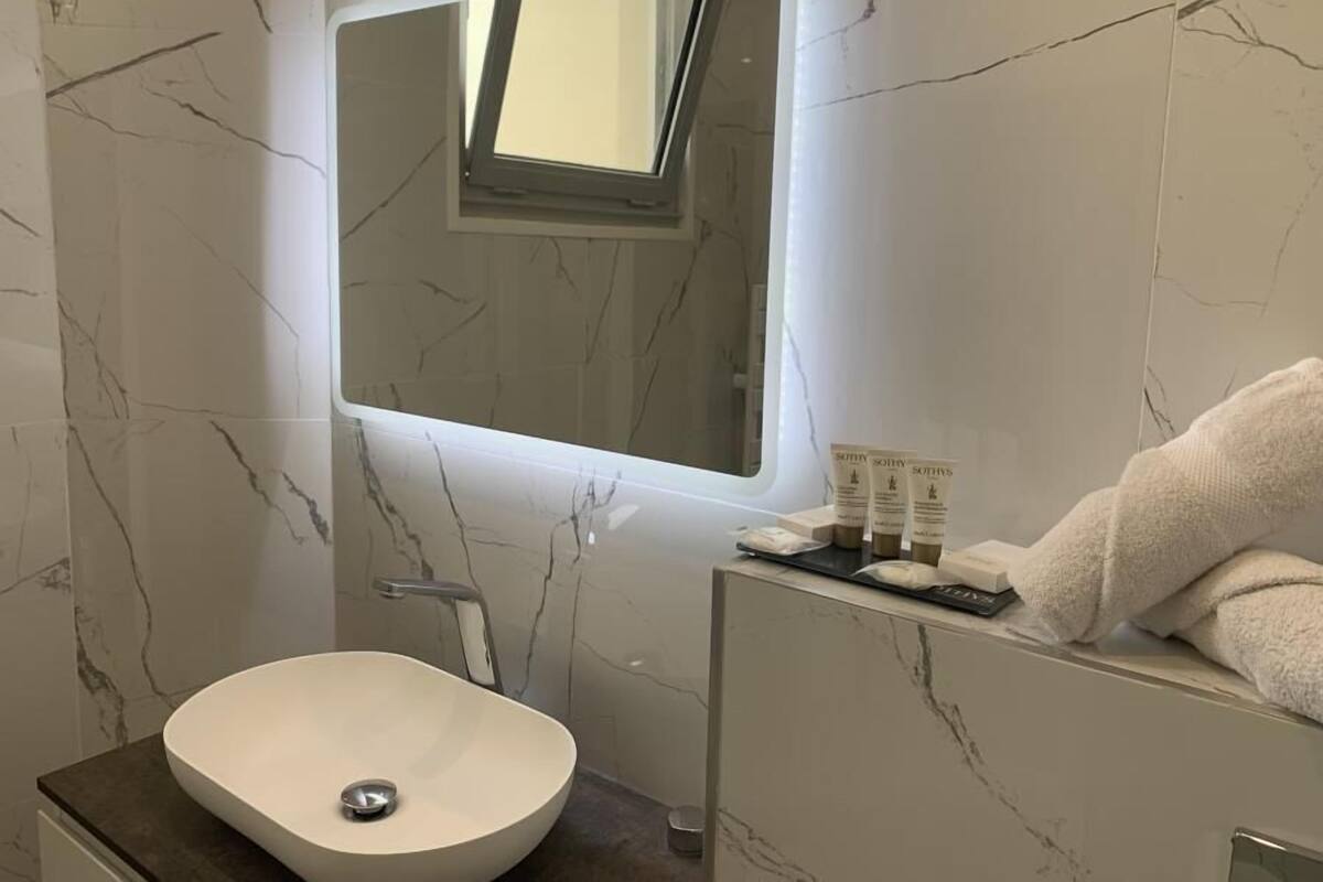A bathroom with a white marble sink, a modern mirror, and a towel on the counter.