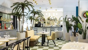 A restaurant interior with checkered flooring, multiple seating areas, and a bar with a visible wine selection. - Hotel des Palmiers (Hyères)