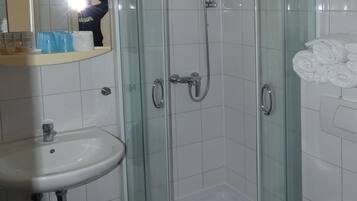 A bathroom with a glass-enclosed shower, a sink, and a toilet.