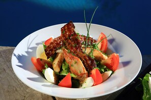 Un plato de comida con varios ingredientes, entre ellos tomates, lechuga y carne.
