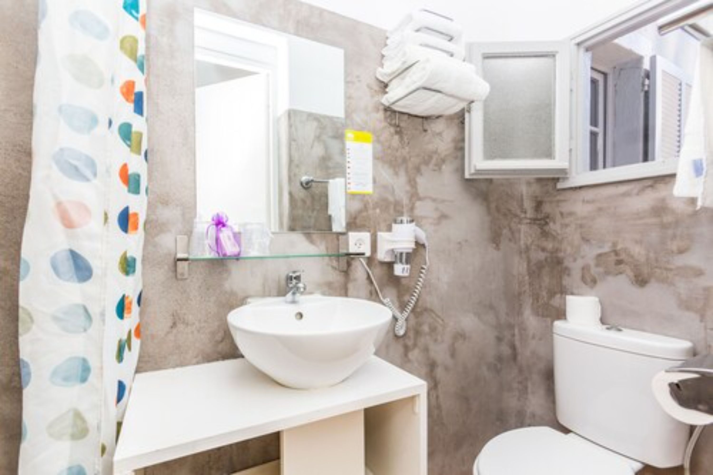 A bathroom with a white sink, toilet, and shower curtain.
