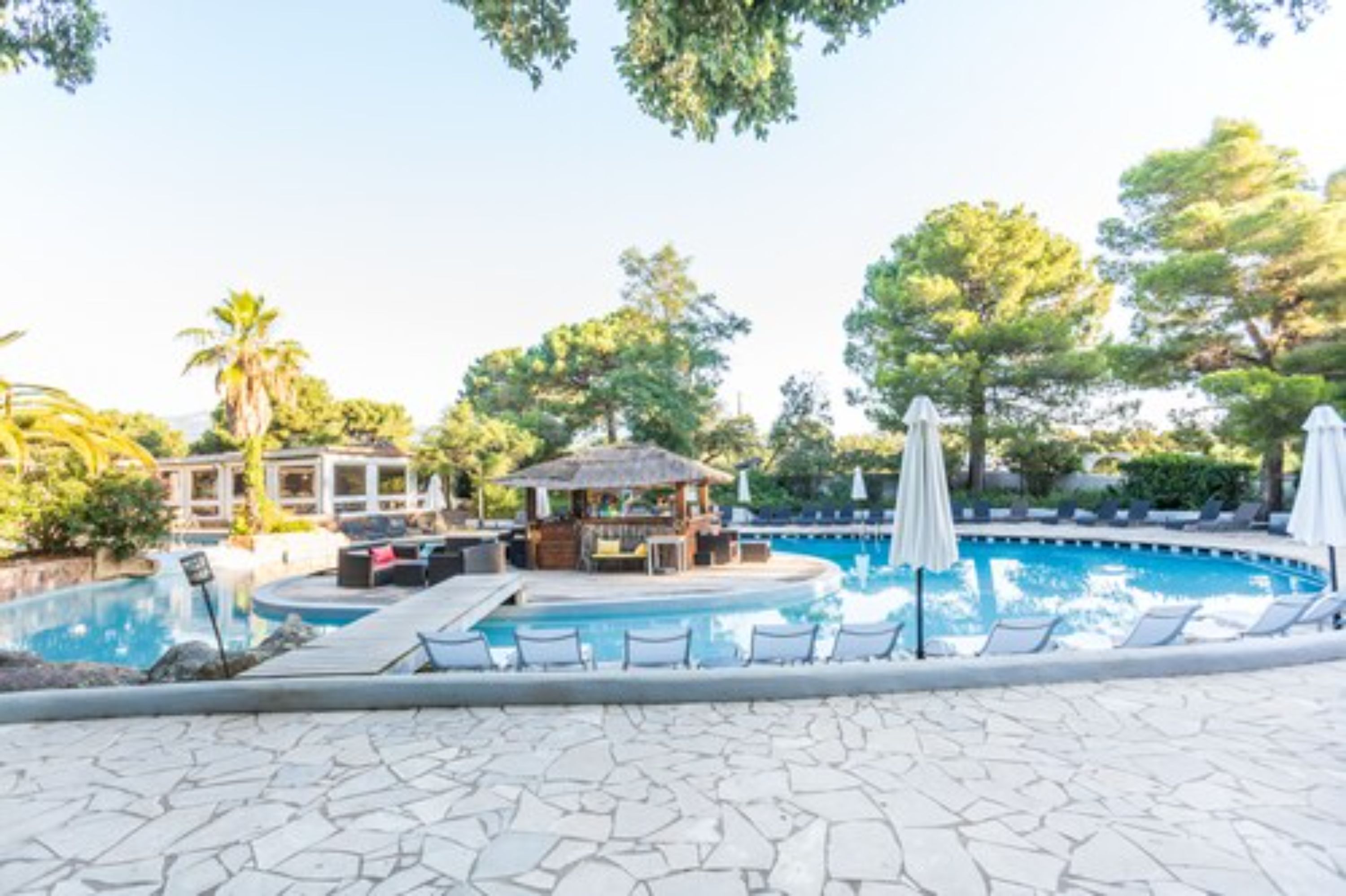 Un espace piscine comprenant des chaises longues, un bar et un kiosque.