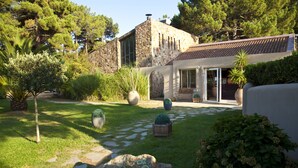Una casa de piedra con un sendero en el jardín, plantas en macetas y una gran roca.