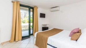 Habitación de hotel con cama, televisión, una mesita pequeña y ventana corredera al exterior.