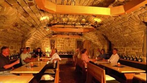 An indoor restaurant with stone walls, wooden tables, and benches. - Hotel Ritschlay (Bollendorf)