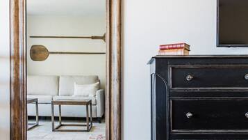 A room with a large mirror, a black dresser, a sofa, and a patterned rug.