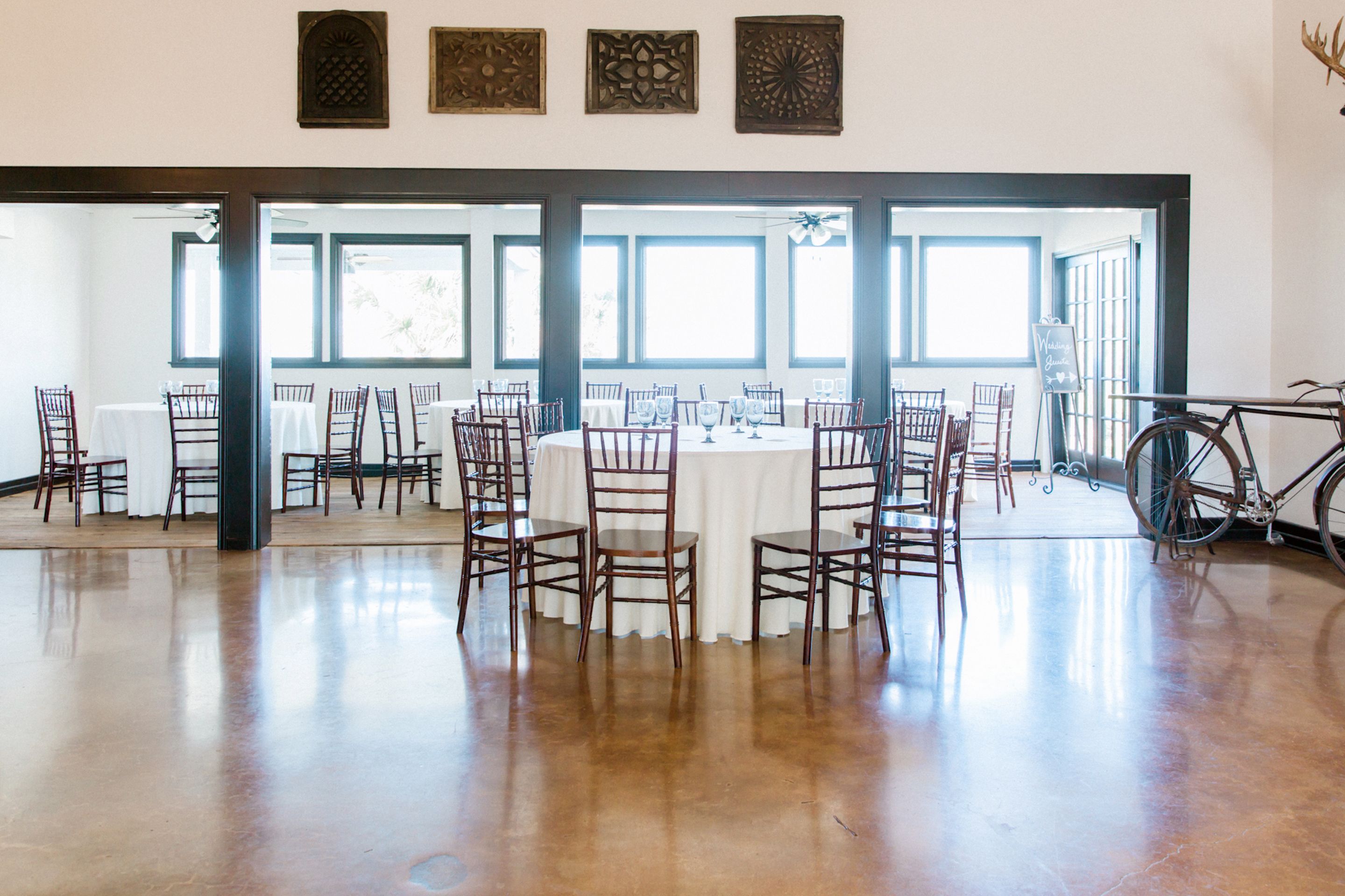 A spacious room with a polished wooden floor, a round table with chairs, and a bicycle in the corner.