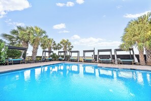 Une piscine avec des chaises longues et des palmiers.