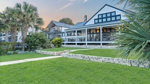 Ein modernes Haus mit großer Veranda, Steinmauern und einem gepflegten Rasen.