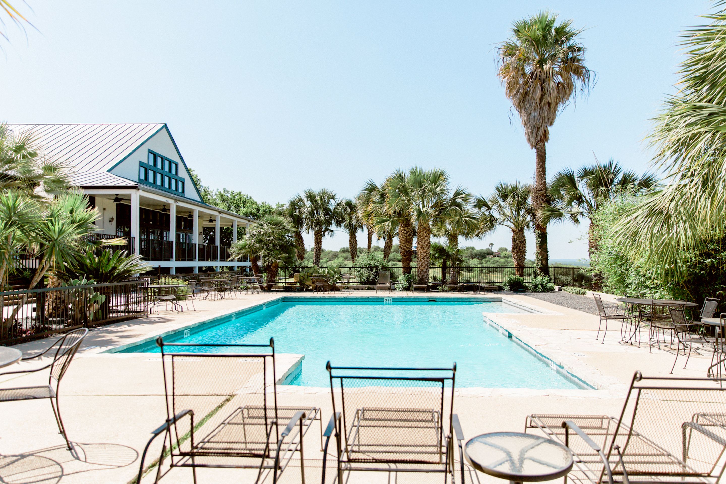 A pool area with lounge chairs and a building with a blue and white facade.