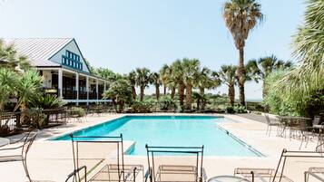 A pool area with lounge chairs and a building with a blue and white facade.