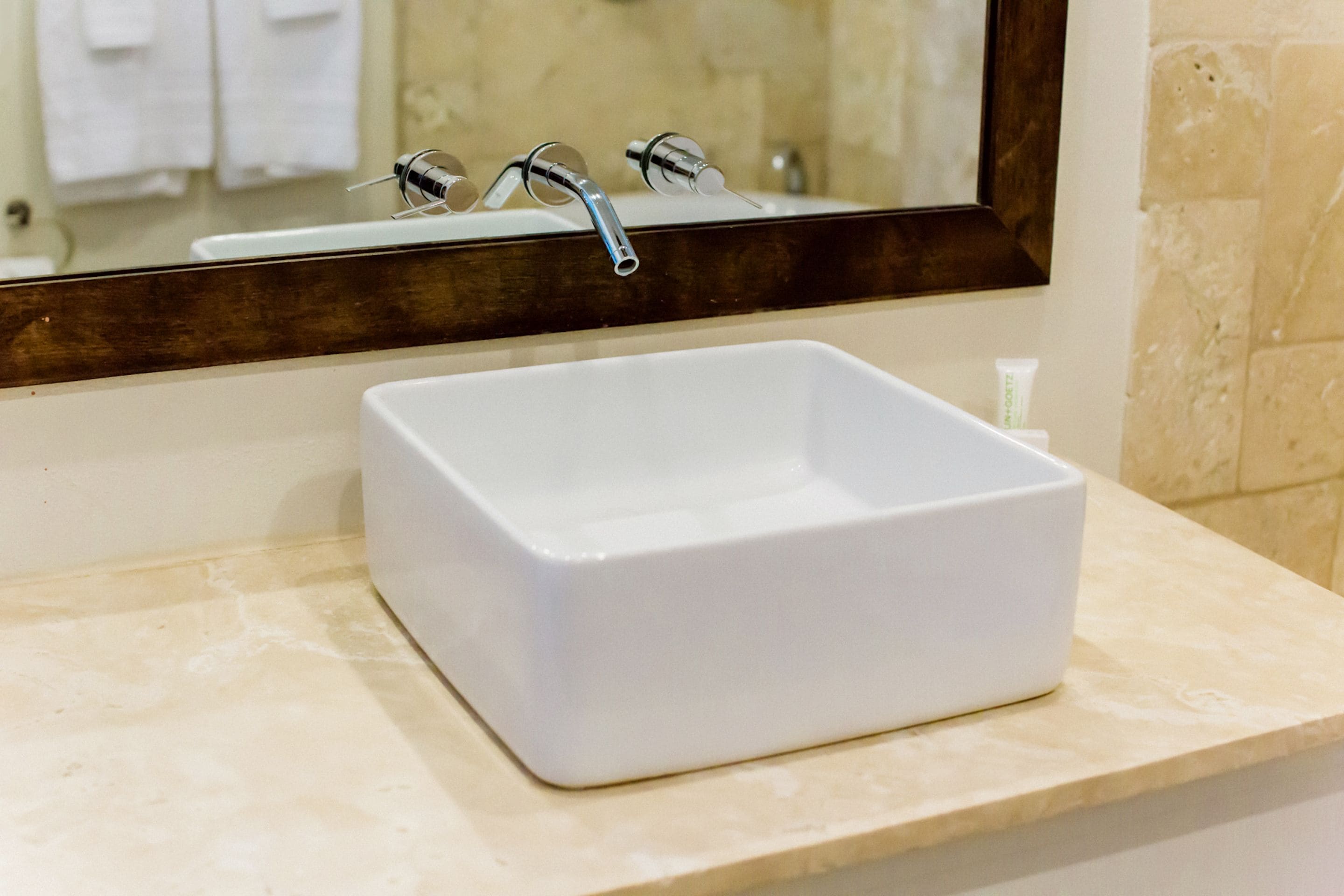 A white rectangular sink with a single faucet on a beige countertop.