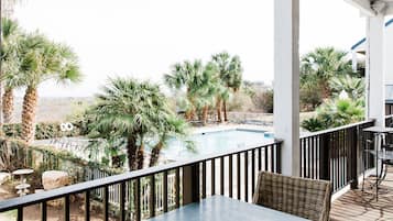 An outdoor patio with a pool, palm trees, and a view of the surrounding landscape.