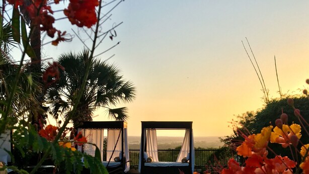 Ein Poolbereich mit Liegestühlen und Blick auf den Sonnenuntergang.