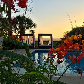 Ein Poolbereich mit Liegestühlen und Blick auf den Sonnenuntergang.