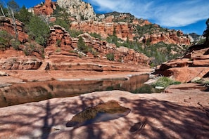 A natural landscape with a river, rocky formations, and sparse vegetation.