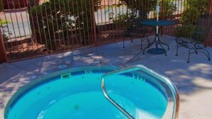 A swimming pool with a metal ladder, surrounded by a fence and a patio area with outdoor furniture. - Baby Quail Inn (Sedona)