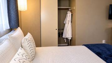 Une chambre d’hôtel avec un lit, un peignoir suspendu à un porte-manteau et une table de chevet.