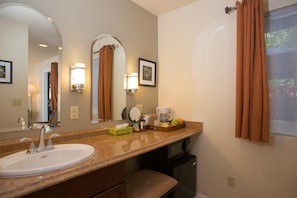 A hotel bathroom with a sink, mirror, towel rack, and a coffee maker on the counter.