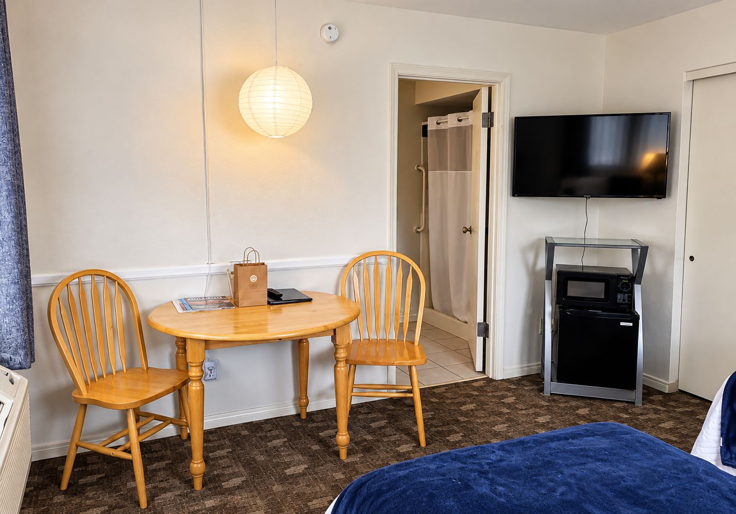 Een hotelkamer met een bed, een televisie, een magnetron en een tafel met stoelen.