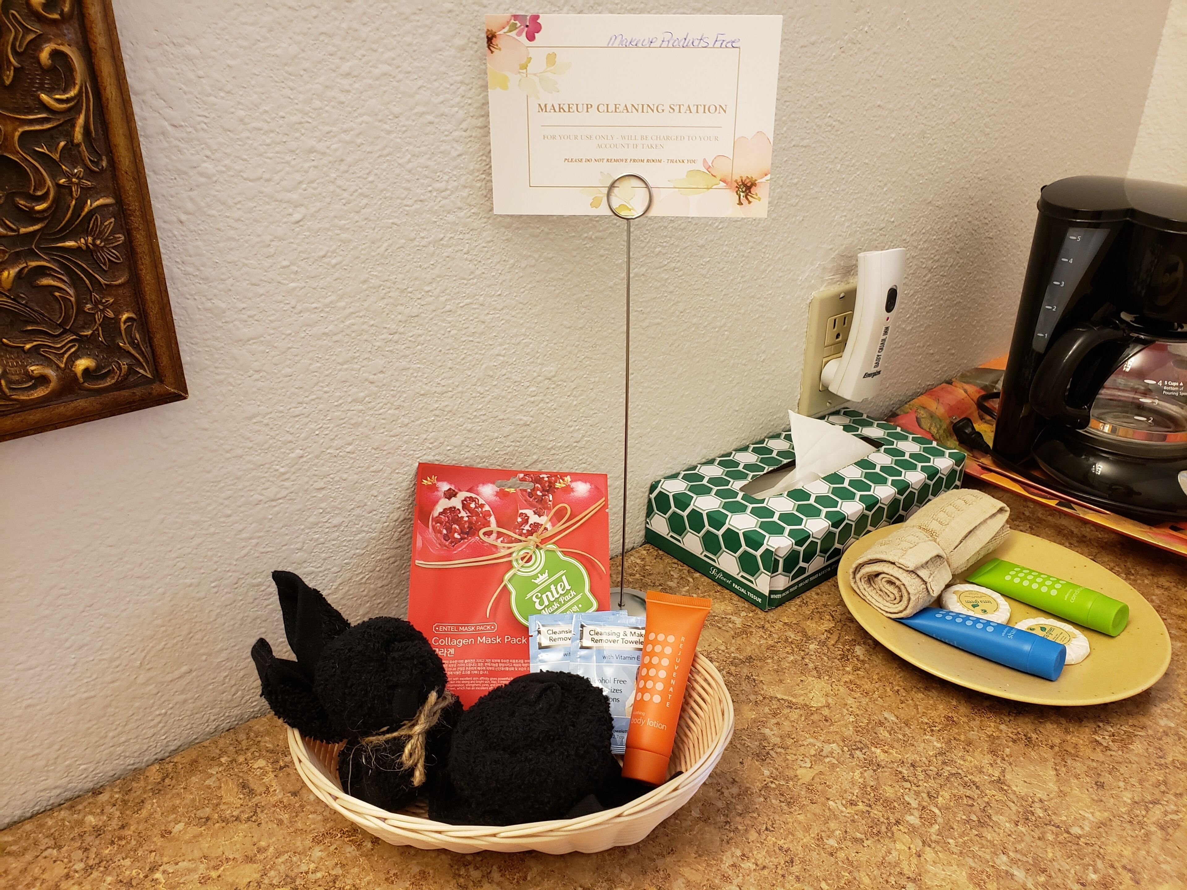 Un espace dédié au nettoyage des pinceaux de maquillage, avec un panneau indicateur, un panier contenant des articles de toilette et une machine à café.