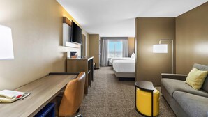 A hotel room with a desk, chair, bed, sofa, and a small trash bin. - Comfort Suites El Paso West (El Paso)