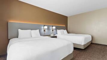 Habitación de hotel con dos camas, cabecera con iluminación integrada, mesita de noche y piso alfombrado.