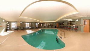 An indoor swimming pool with a curved design, surrounded by tables and chairs, and a bar area. - Comfort Suites El Paso West (El Paso)