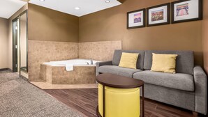 A modern bathroom with a bathtub, a gray sofa with yellow pillows, and framed pictures on the wall. - Comfort Suites El Paso West (El Paso)