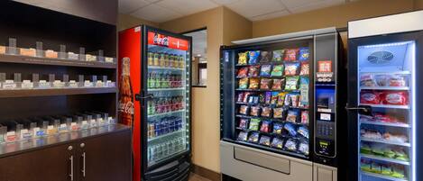 A vending area with a Coca-Cola refrigerator, snack vending machines, and a refrigerated display case.