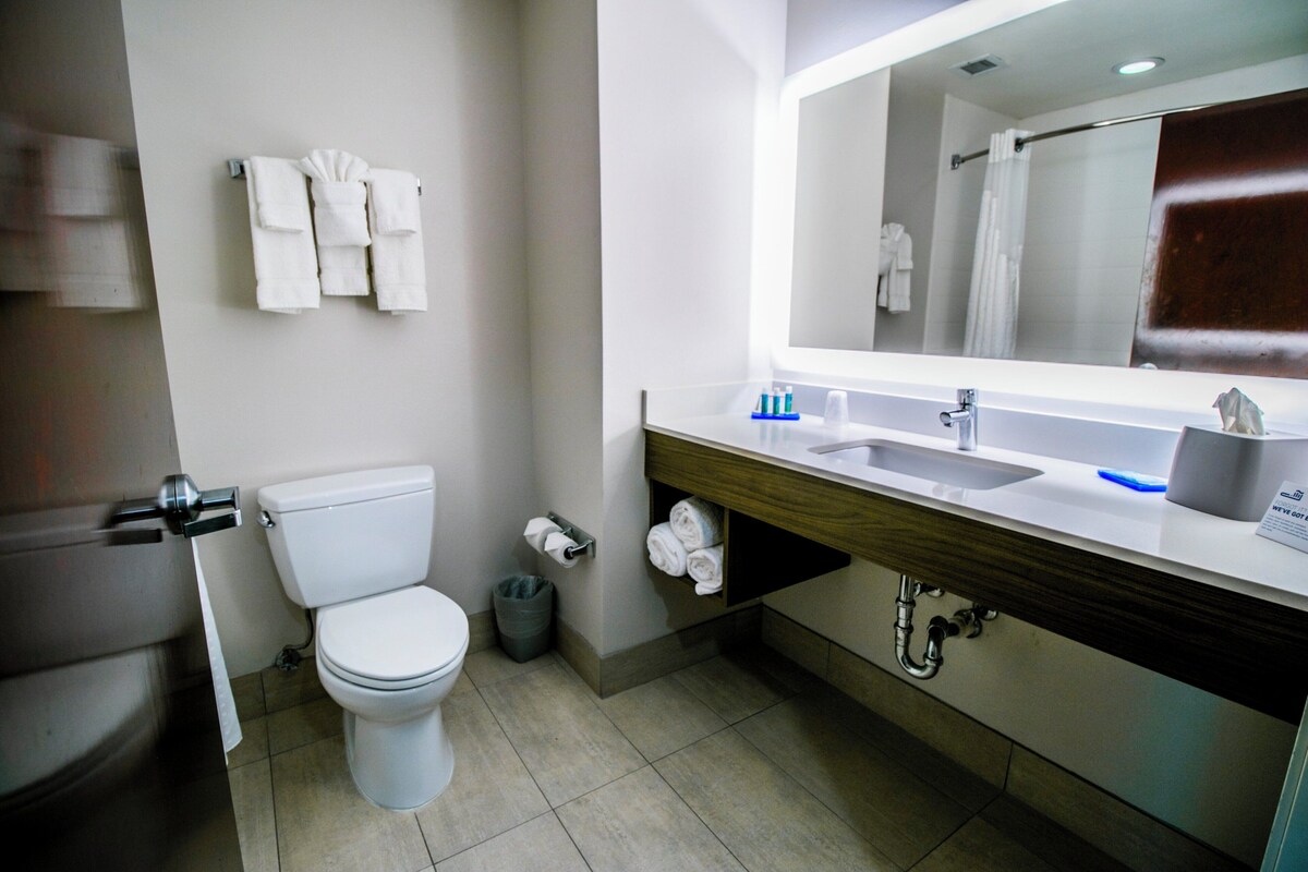 A modern bathroom with a toilet, sink, mirror, and towel rack.