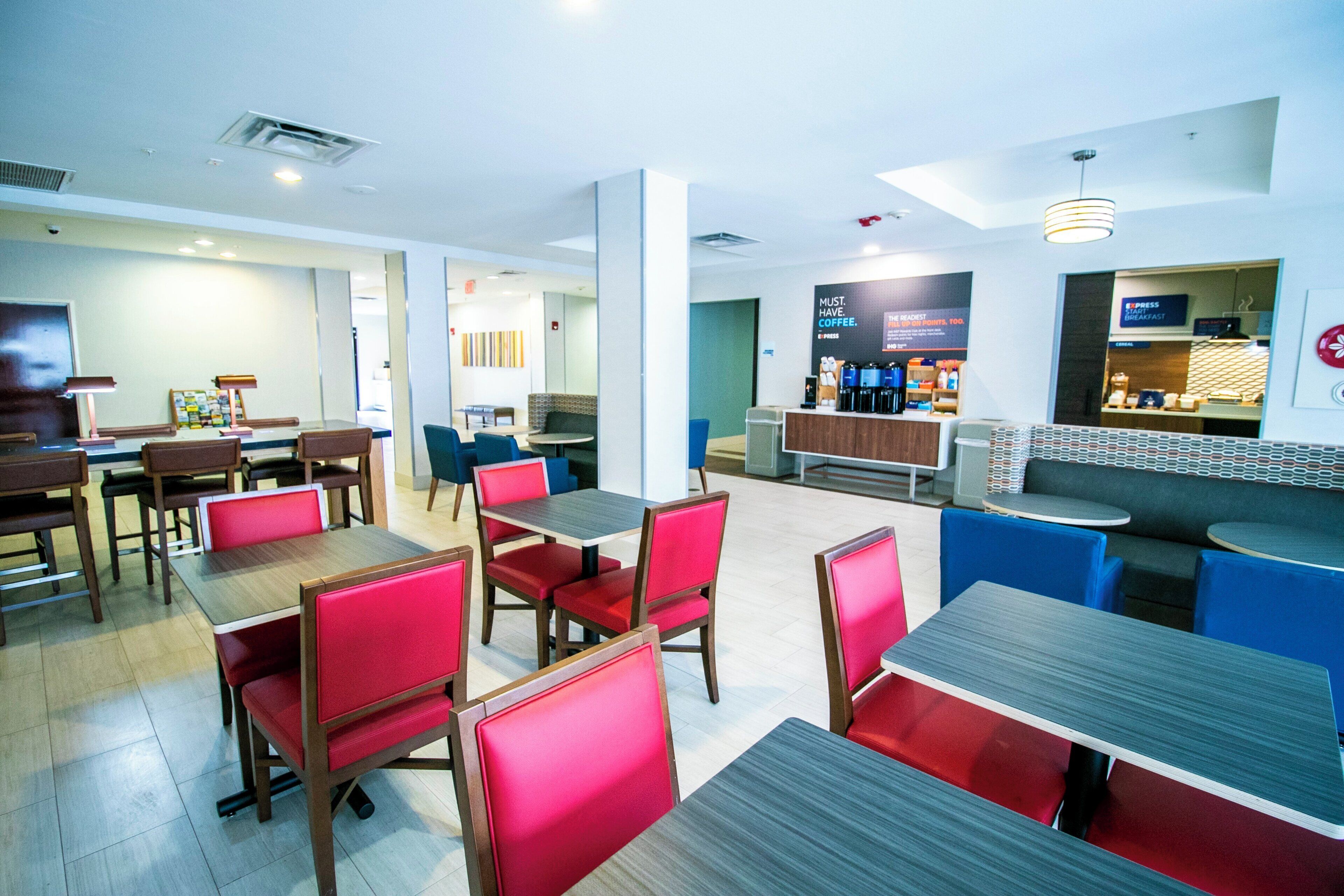 A modern cafe with multiple seating areas, including tables and booths, and a coffee bar in the background.