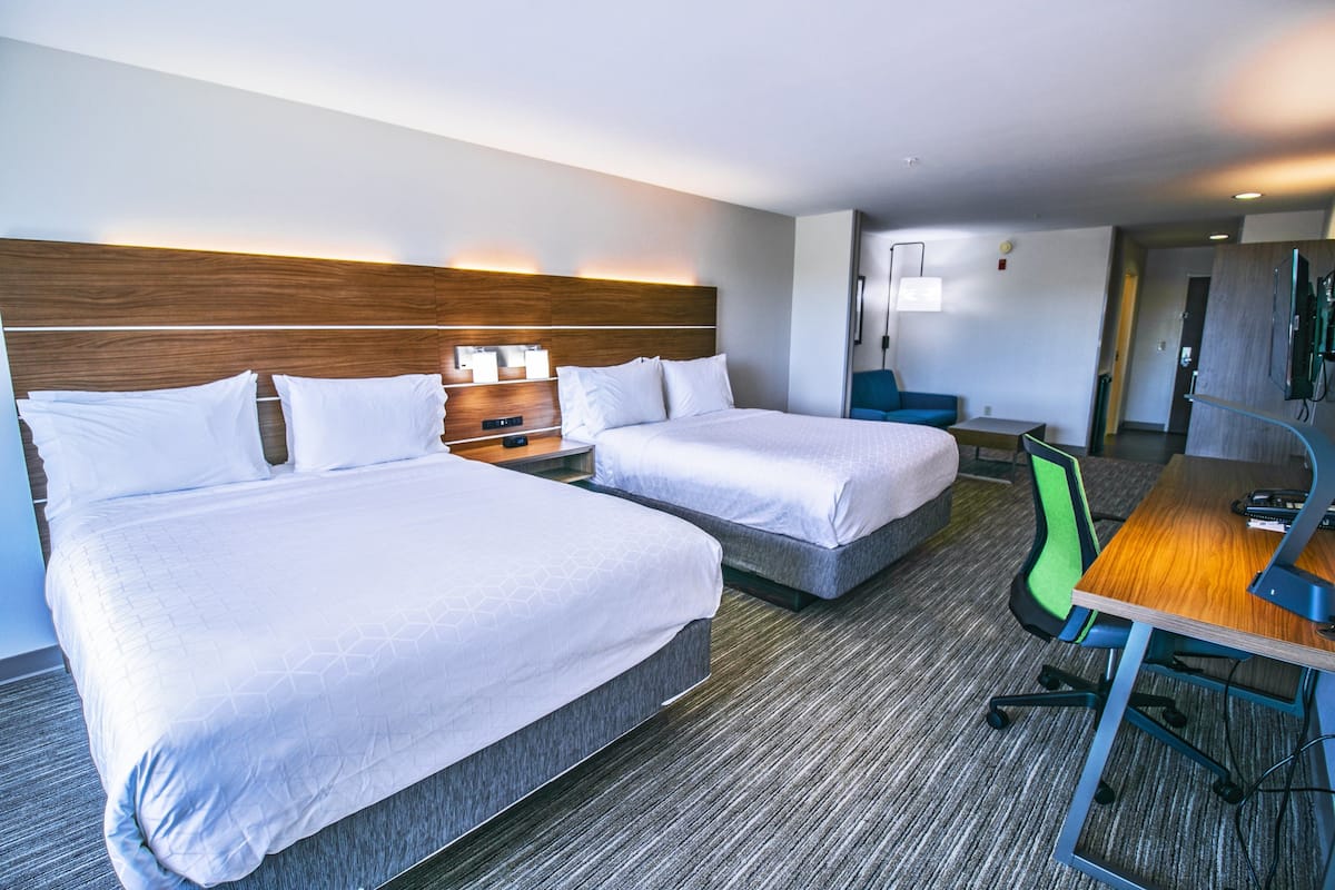 Une chambre d’hôtel avec deux lits, un bureau, une chaise et un téléviseur.