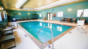 A swimming pool with a lifebuoy, chairs, and a changing room.