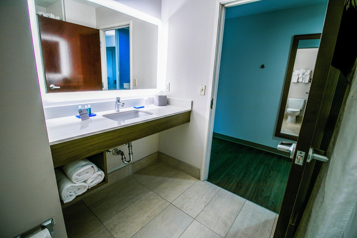 A bathroom with a sink, mirror, and towel storage.