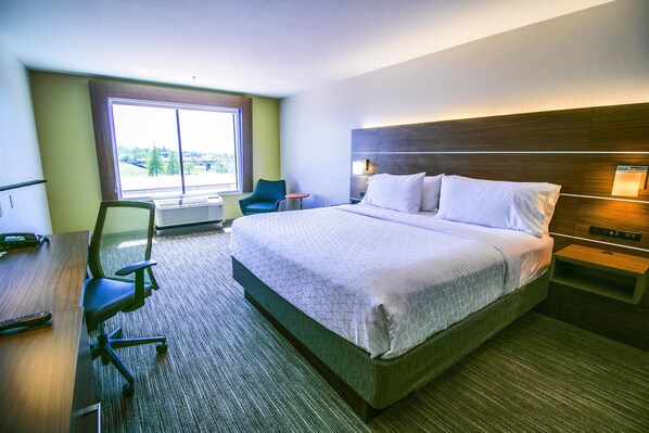 A hotel room with a large bed, a desk with a chair, a small table, and a window with a view. - Holiday Inn Express Hotel & Suites, a Baton Rouge-Port Allen by IHG (Port Allen)