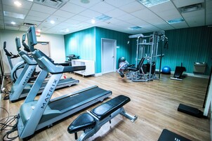 Un gimnasio con cintas de correr, una banca y equipo de levantamiento de pesas.