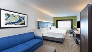 A hotel room with a bed, a blue sofa, a desk, and a television. - Holiday Inn Express & Suites Sealy by IHG (Sealy)