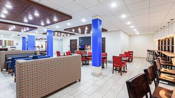 Un amplio espacio interior con diversas opciones de asientos, incluyendo cabinas y mesas, además de una barra probablemente para pedir comida o bebidas.